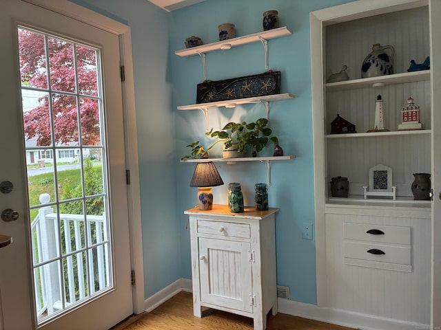 doorway to outside featuring light wood-style flooring, baseboards, and a healthy amount of sunlight