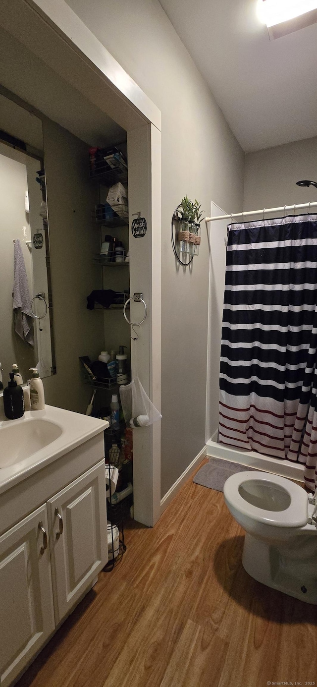 bathroom with a shower with shower curtain, toilet, wood finished floors, and vanity