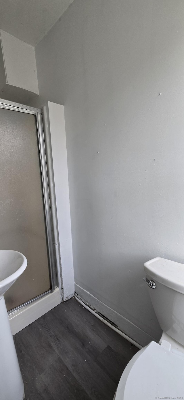 full bathroom with toilet, a shower stall, and wood finished floors