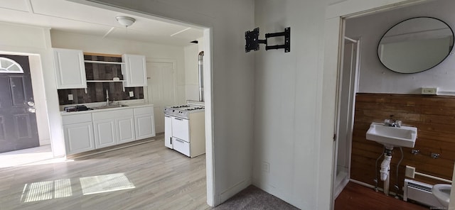 kitchen featuring light countertops, white range with gas cooktop, white cabinetry, a baseboard heating unit, and light wood-style flooring