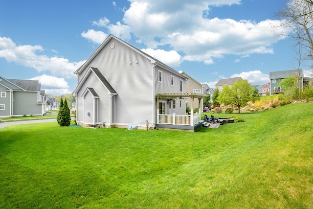 rear view of house featuring a yard, a pergola, and a deck