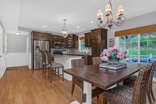 dining space with wainscoting, a chandelier, a decorative wall, recessed lighting, and light wood-style flooring