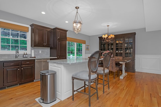 kitchen featuring dark brown cabinetry, a sink, a chandelier, light wood-type flooring, and stainless steel dishwasher