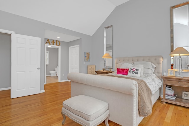 bedroom with connected bathroom, vaulted ceiling, wood finished floors, and a closet