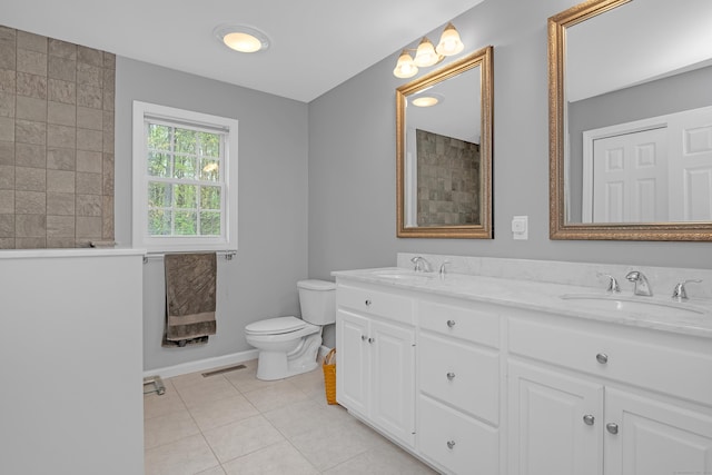 full bathroom with a sink, double vanity, toilet, tile patterned floors, and baseboards
