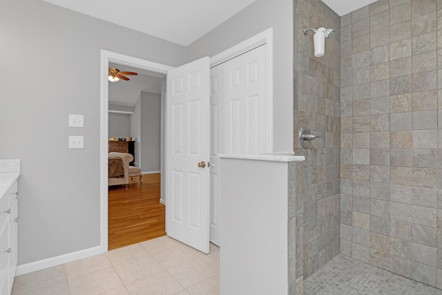 ensuite bathroom with vanity, a ceiling fan, tile patterned floors, and a tile shower