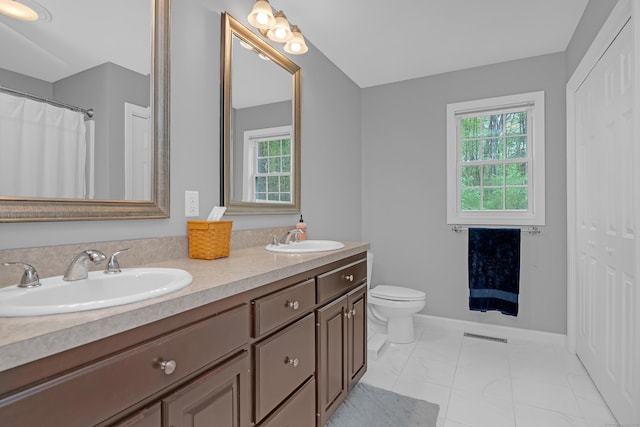 bathroom featuring double vanity, a sink, marble finish floor, and toilet