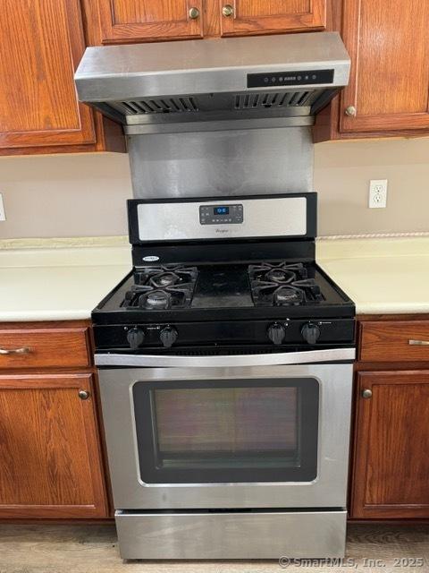 36 Meadowrue Dr Unit 36, Glastonbury, CT 06033 - kitchen featuring under cabinet range hood, gas range, light countertops, and brown cabinets