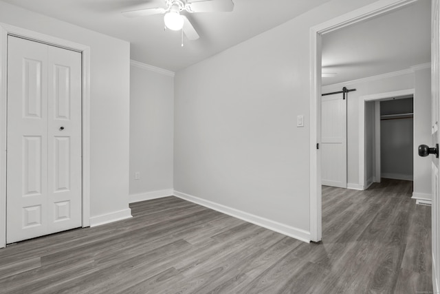 18 Brook St, Shelton, CT 06484 - unfurnished bedroom with wood finished floors, ornamental molding, a barn door, a ceiling fan, and baseboards