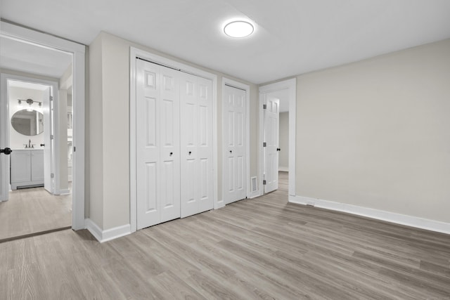 18 Brook St, Shelton, CT 06484 - unfurnished bedroom featuring a sink, baseboards, multiple closets, and wood finished floors