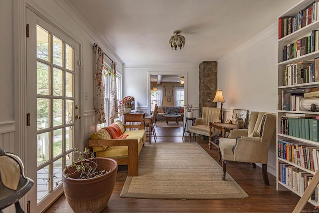 sitting room featuring built in shelves, ornamental molding, a ceiling fan, and wood finished floors