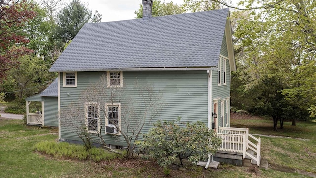 view of side of home with a lawn, a chimney, and roof with shingles