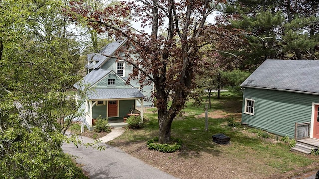 view of front of home with roof with shingles, covered porch, and a front yard