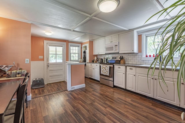 kitchen featuring a wealth of natural light, white microwave, dark wood-style floors, and stainless steel range with electric cooktop