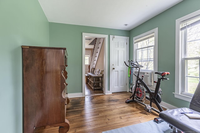 workout area with baseboards, a wealth of natural light, and wood finished floors