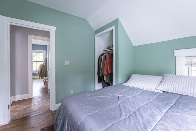 bedroom featuring baseboards, vaulted ceiling, wood finished floors, and a closet
