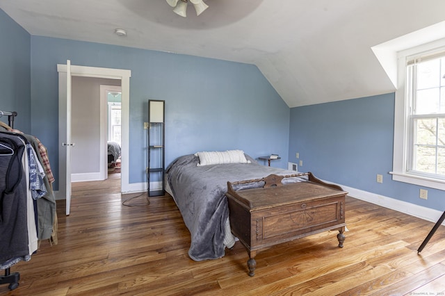 bedroom with multiple windows, wood finished floors, and lofted ceiling