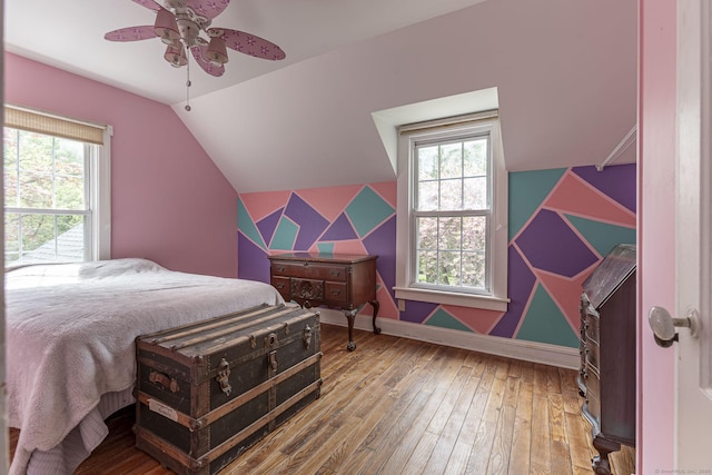 bedroom with wood-type flooring, baseboards, vaulted ceiling, and multiple windows