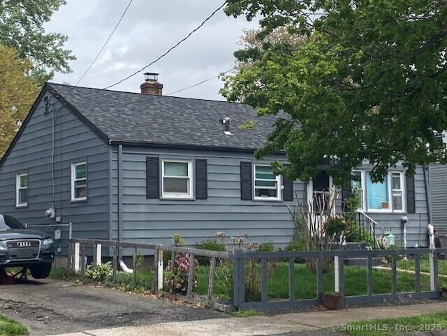view of property exterior with a shingled roof, a fenced front yard, and a chimney