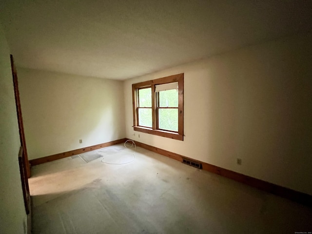 empty room with concrete flooring, baseboards, and visible vents