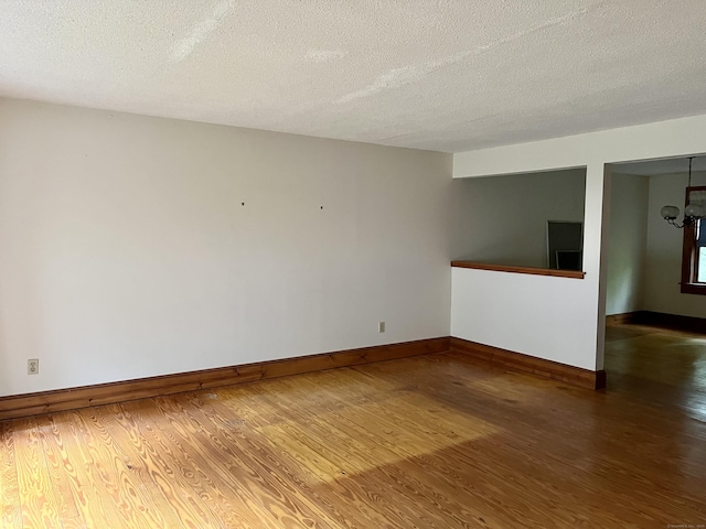 unfurnished room featuring a textured ceiling, baseboards, and wood finished floors