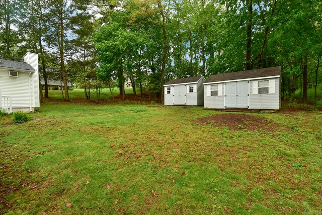 view of grassy yard featuring a storage shed, an outdoor structure, and view of scattered trees