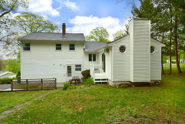 back of house with a chimney, a lawn, and a shingled roof