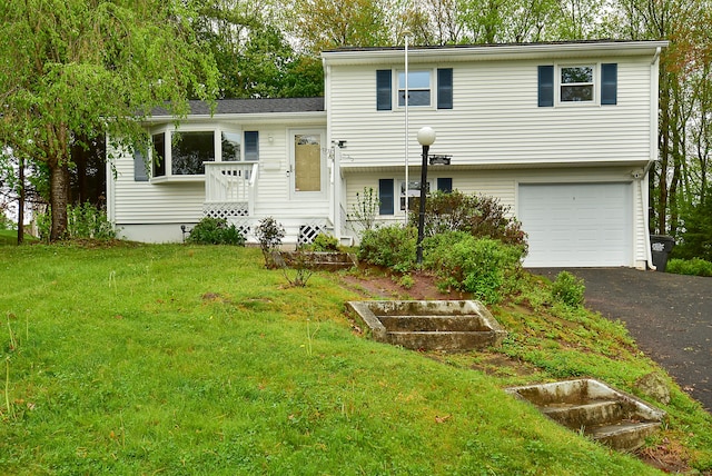 split level home featuring a garage, a front lawn, and asphalt driveway