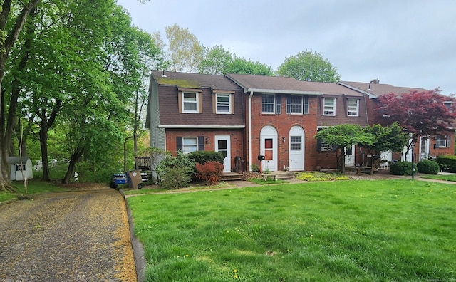 colonial home with brick siding, a front yard, and aphalt driveway