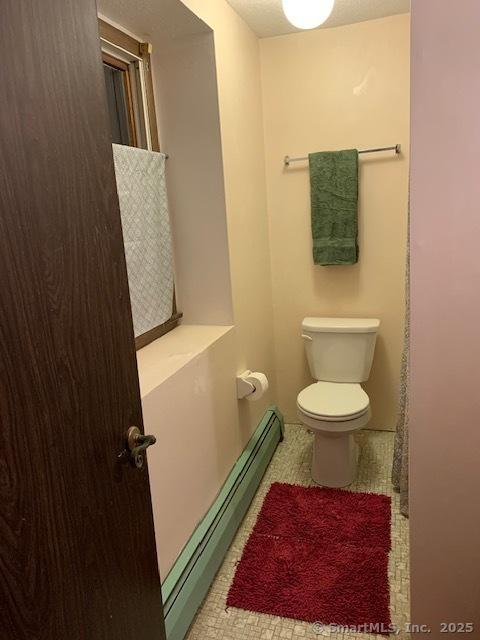 bathroom with tile patterned flooring, a baseboard radiator, and toilet