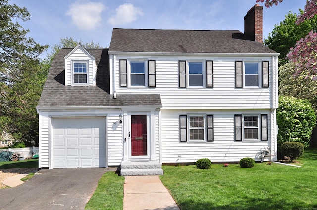 view of front of house with a chimney, a front yard, roof with shingles, and a garage