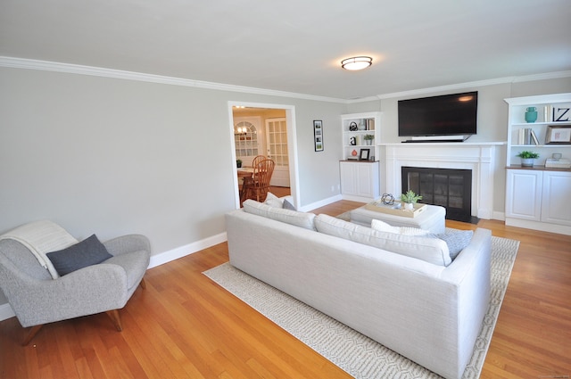 living area featuring baseboards, ornamental molding, built in shelves, a fireplace with flush hearth, and wood finished floors