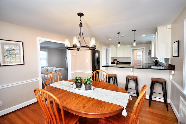 dining space featuring a chandelier, recessed lighting, baseboards, and light wood-style floors