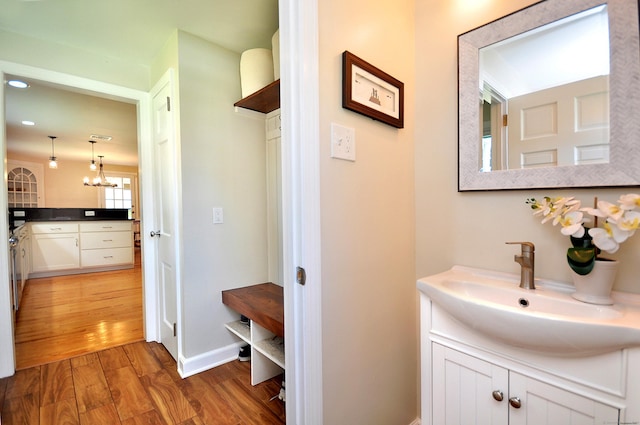 bathroom with baseboards, a notable chandelier, vanity, and wood finished floors