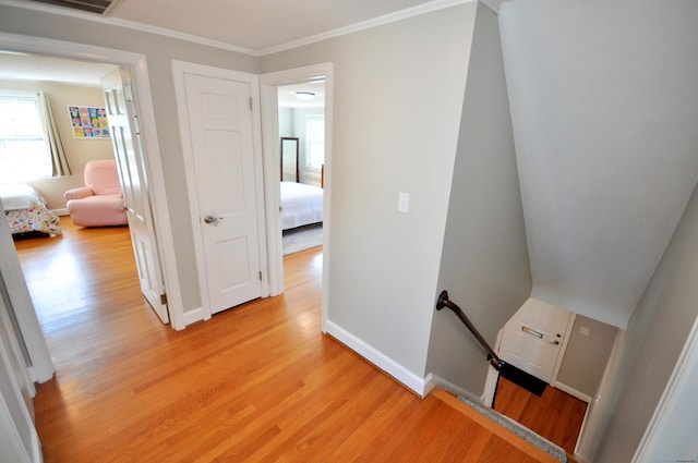hallway with light wood-style floors, an upstairs landing, and baseboards