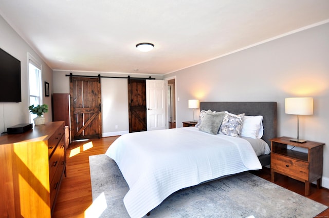 bedroom featuring light wood finished floors, a barn door, and baseboards