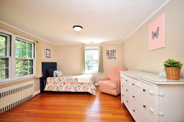 bedroom featuring baseboards, radiator, light wood-style floors, and crown molding