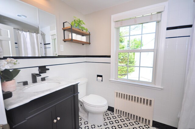 full bath featuring toilet, tile walls, a healthy amount of sunlight, and radiator heating unit