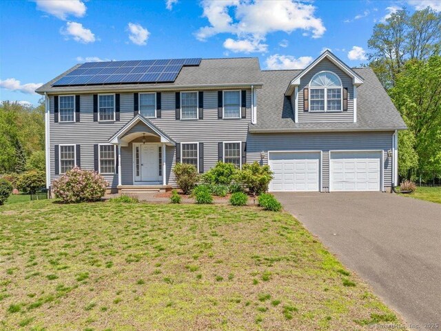 149 Tromley Rd, East Windsor, CT 06088 - colonial house with driveway, roof mounted solar panels, a front lawn, and a garage