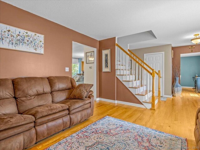 149 Tromley Rd, East Windsor, CT 06088 - living room featuring stairway, wood finished floors, baseboards, and a textured ceiling