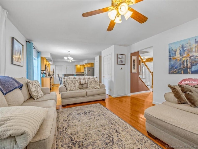 149 Tromley Rd, East Windsor, CT 06088 - living room with stairs, a chandelier, light wood-type flooring, a ceiling fan, and baseboards