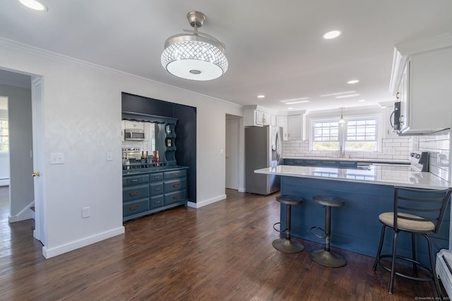kitchen featuring a peninsula, tasteful backsplash, dark wood-style floors, white cabinets, and appliances with stainless steel finishes