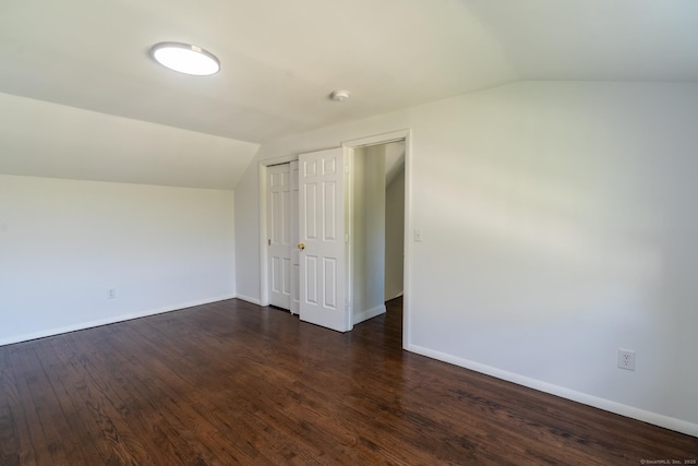 unfurnished bedroom with lofted ceiling, baseboards, a closet, and dark wood finished floors