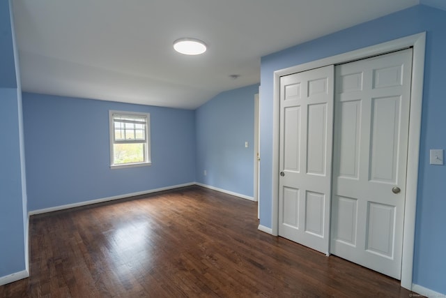 unfurnished bedroom with baseboards, dark wood-style floors, and vaulted ceiling