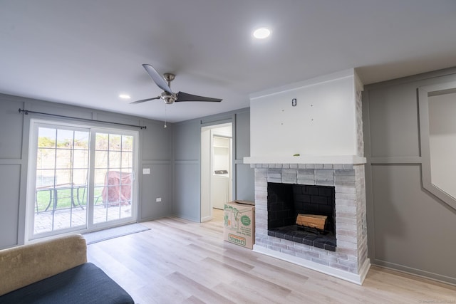 living room with a ceiling fan, light wood-style floors, a fireplace, and recessed lighting
