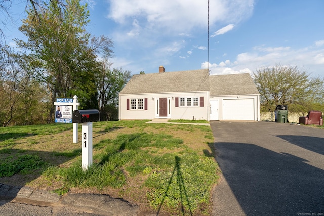 new england style home with an attached garage, a chimney, a front lawn, and aphalt driveway