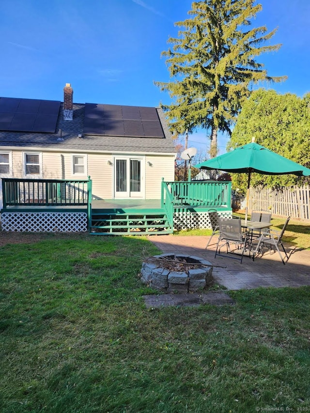 back of house featuring an outdoor fire pit, roof mounted solar panels, a patio, and a yard