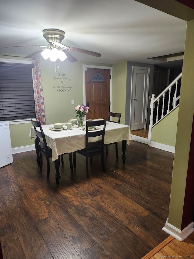 dining space with baseboards, wood finished floors, a ceiling fan, and stairs