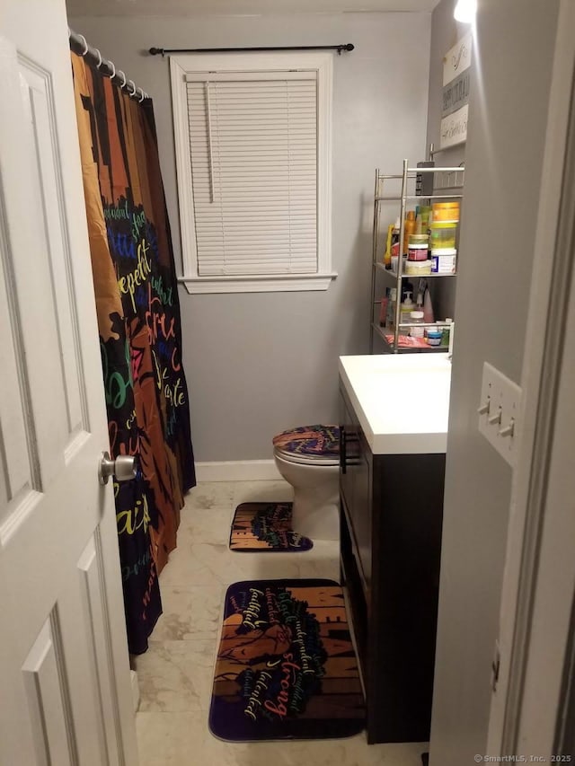 full bath featuring toilet, a shower with shower curtain, baseboards, marble finish floor, and vanity