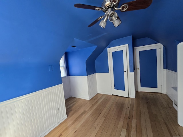 bonus room featuring wainscoting, lofted ceiling, hardwood / wood-style floors, and a ceiling fan